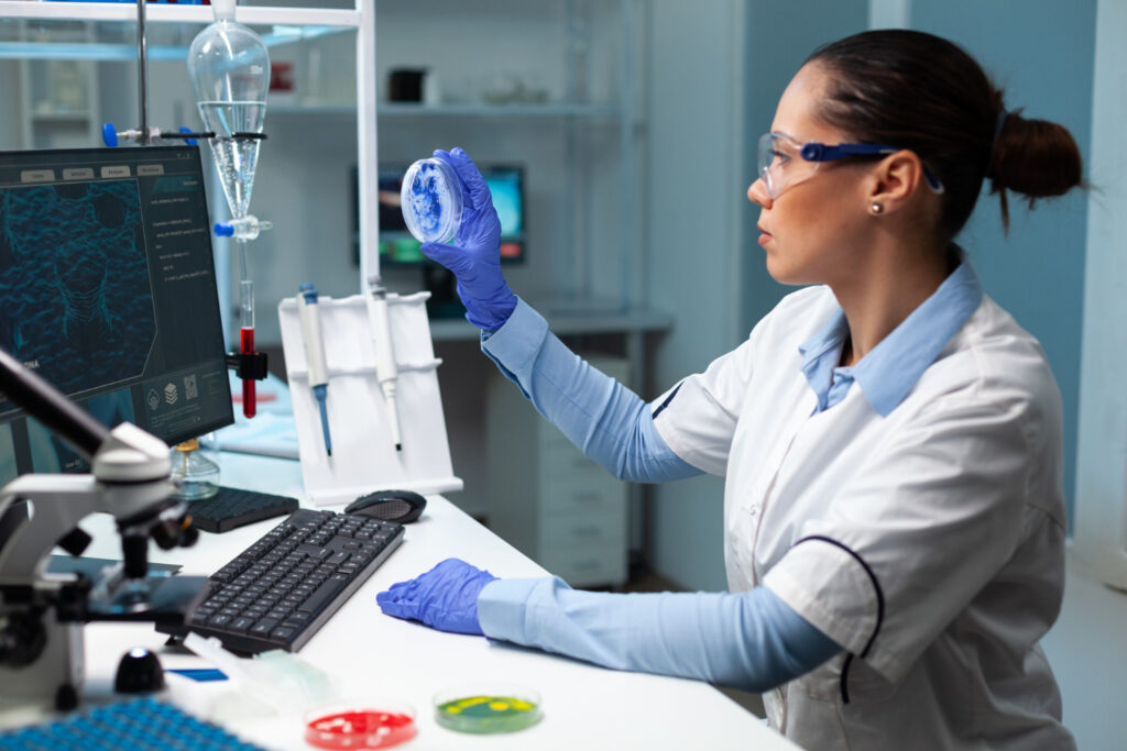 Female scientist examining a petri dish in a modern laboratory.
