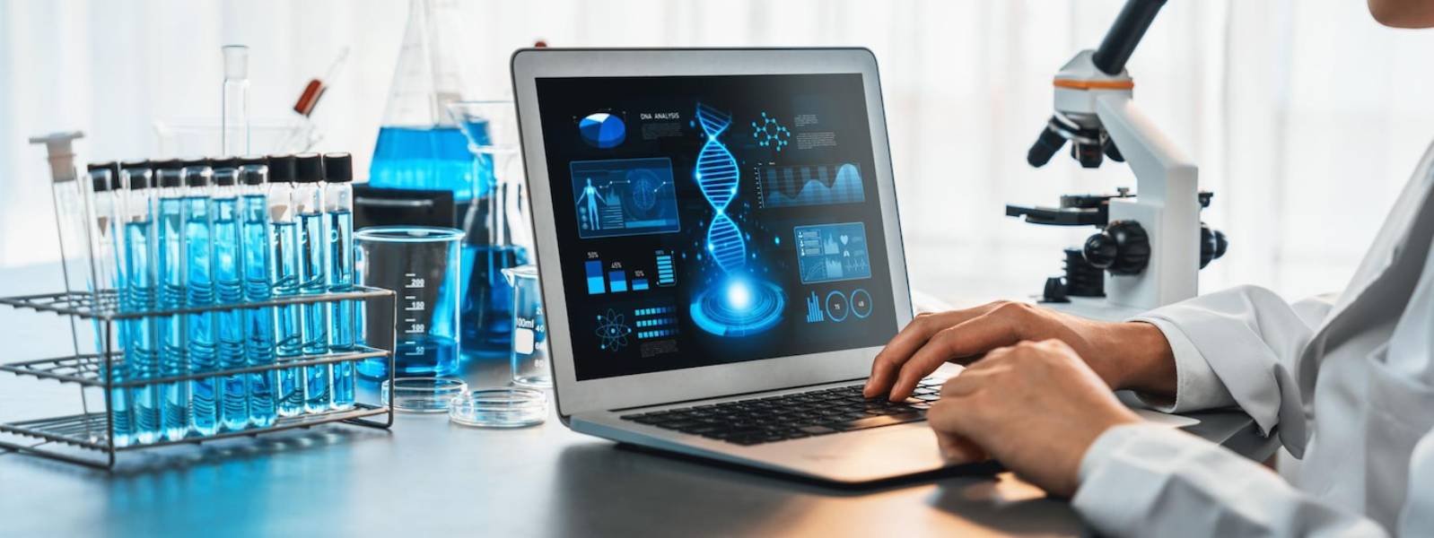 A scientist in a lab examines DNA analysis on a laptop, surrounded by blue solutions in glassware and a microscope.