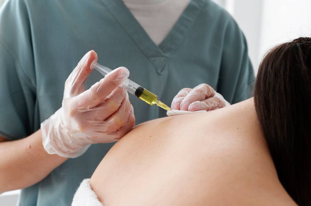 A healthcare professional administers an injection into a patient's shoulder while wearing gloves