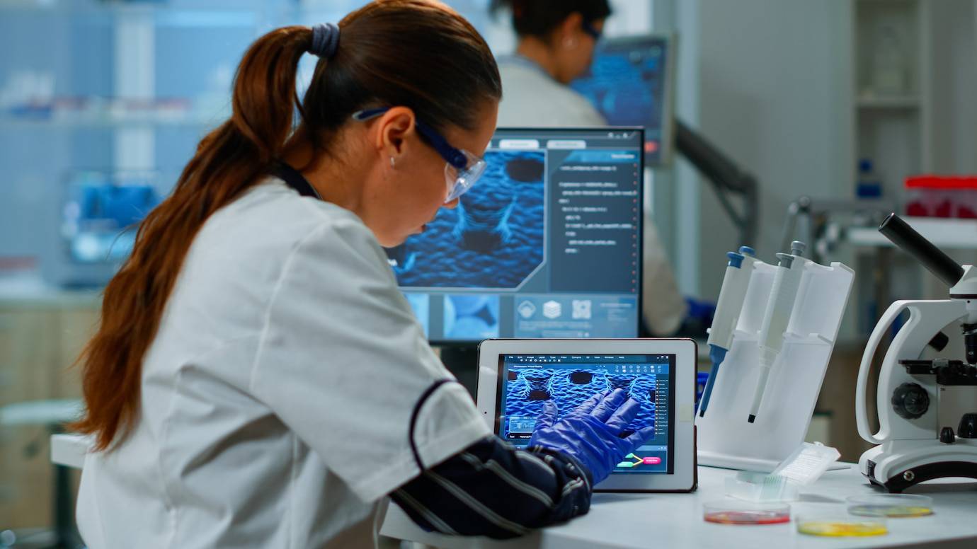 Female scientist analyzing 3D molecular structures on computer screens in a laboratory.