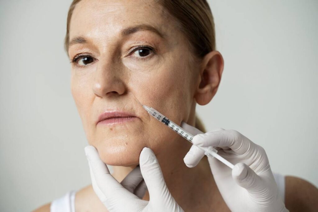 A mature woman receives a facial injection from a healthcare professional wearing gloves.