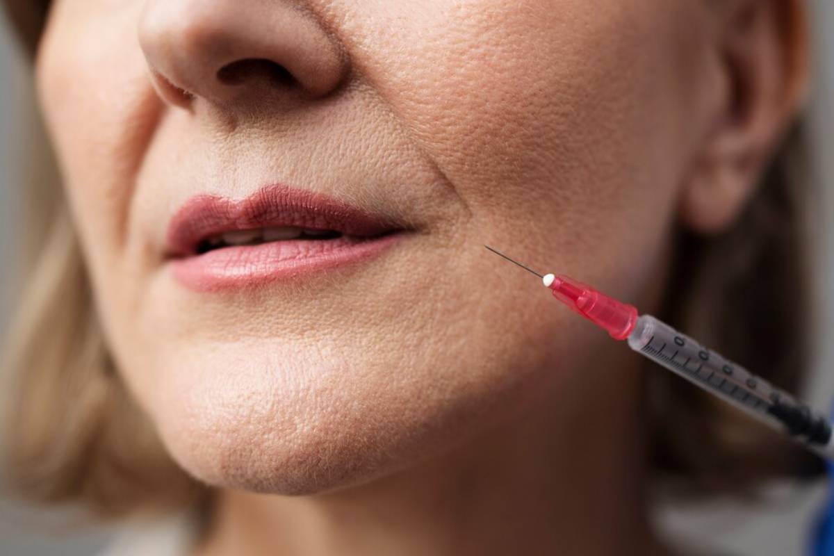Close-up of a mature woman receiving a facial injection with a syringe.