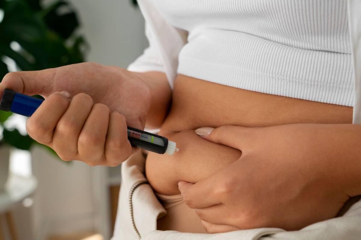 A person injects medication into their abdomen using a pen device, showcasing diabetes management