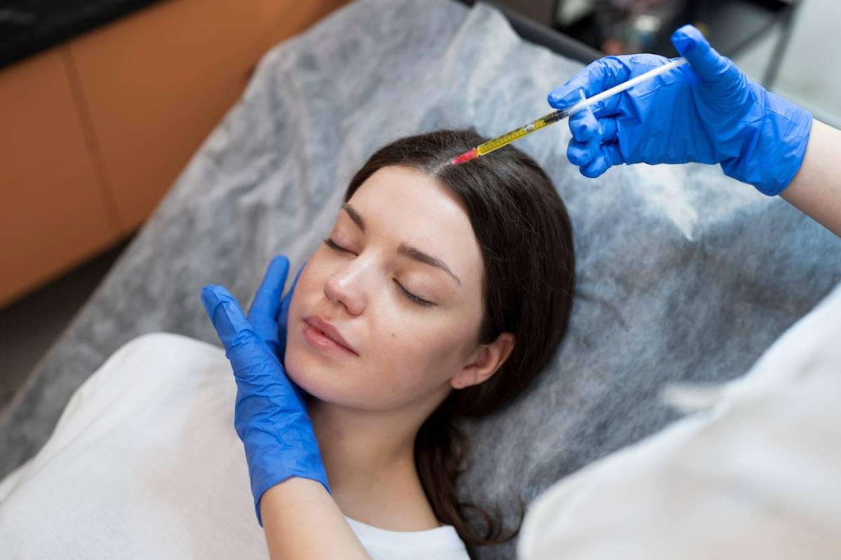 A healthcare professional in blue gloves prepares an injection above a patient lying on a treatment bed