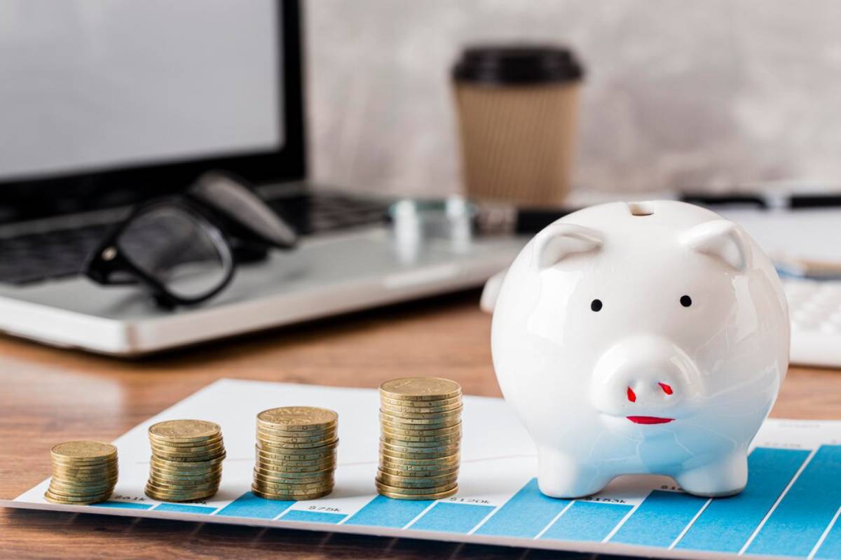 A white piggy bank sits beside stacks of coins and a financial chart