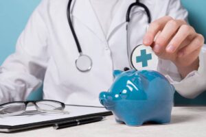 A healthcare professional in a lab coat deposits a health symbol coin into a blue piggy bank