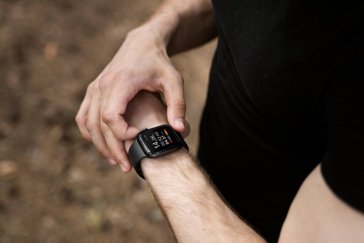 Person checking a fitness tracker on their wrist during a workout outdoors.