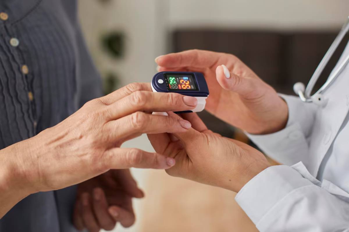 A healthcare professional is using a pulse oximeter on a patient's finger to measure oxygen saturation.