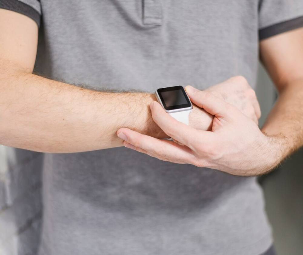 Close-up of a man interacting with his smartwatch, focusing on his hands and the device.